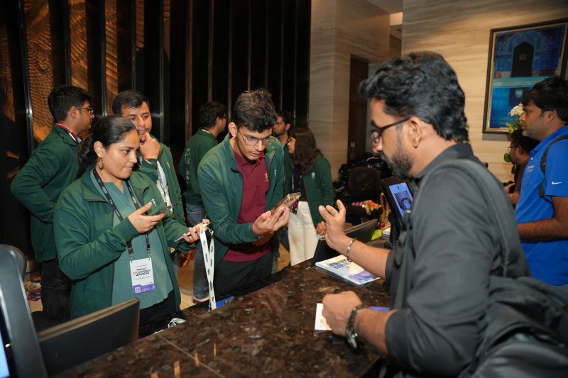 Nimitt in a green volunteer jacket checking in an attendee at the Product UnConference registration desk