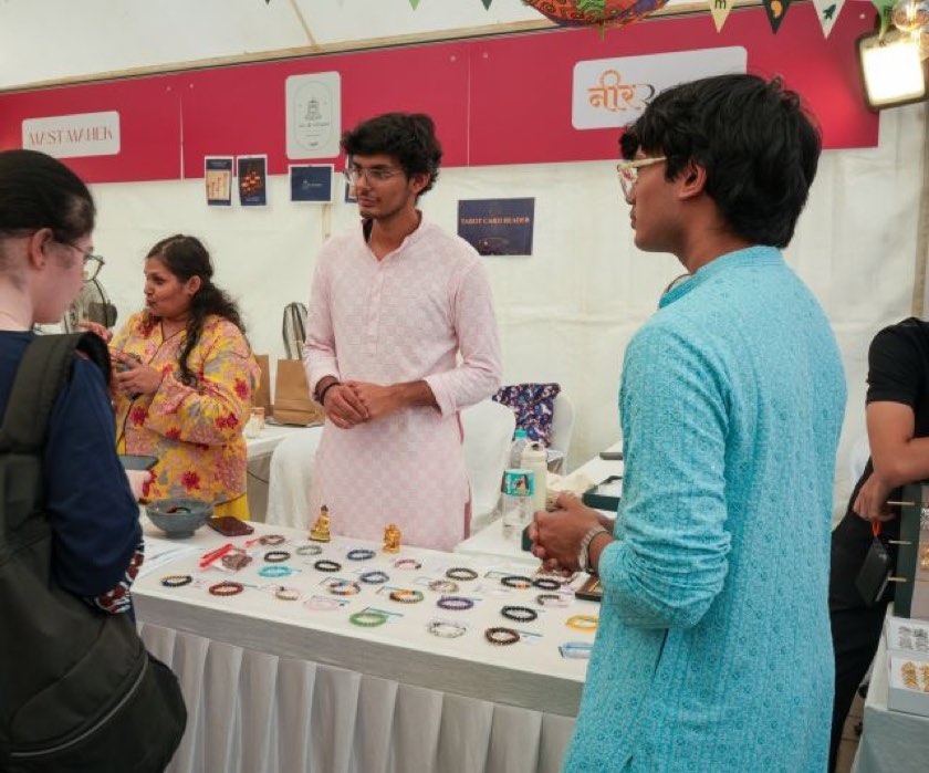 Nimitt behind the Neer Ratna stall at an offline flea market, bracelets laid out on the table